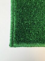 Close-up of the corner of a rectangular Graveside Grass mat in green, displayed on a white surface.