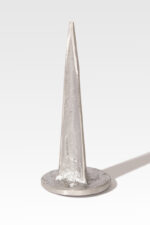 A metal cone sculpture with a rough texture, similar to the Cast Aluminum Lot Markers, is mounted on a flat base and projects a shadow to the right against an unadorned background.