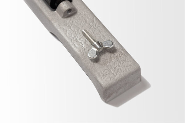 Close-up of a silver metal wingnut on a textured gray lever, evoking the industrial style of Casket Roller Bars, with a small black component at the top left corner.