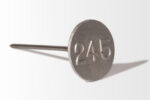 This Cast Aluminum Lot Marker is a sleek metal nail with a round head, engraved with the number "245" on a pristine white background.