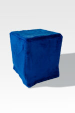 A cube-shaped ottoman with a blue velvet cover elegantly stands against a light gray backdrop, echoing modern sleek designs and adding sophistication similar to the EZ Fold Cremation Stand.