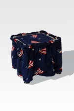 A compact square stool, topped with blue fabric displaying American flags and stars, elegantly transforms into a Stainless Steel Cremation Stand.