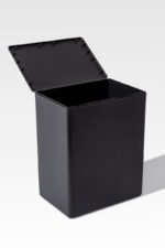 A temporary cremation container in black with a rectangular shape and hinged lid stands against a plain background, showcasing its minimalist design.