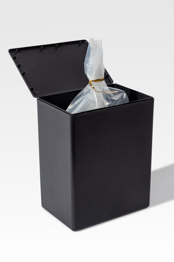 A black trash bin with its lid open, similar to Temporary Cremation Containers, contains a clear plastic bag secured with a twist tie.