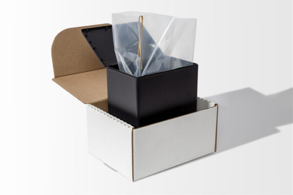 The product, Temporary Cremation Containers, includes a black rectangular container with a transparent plastic liner and is packaged in an open white cardboard box.