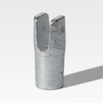 A Frame Fittings metal clevis, featuring dual prongs and a hole near the top, stands upright on a smooth surface.