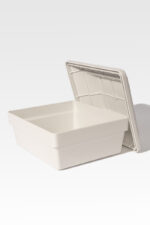 A Cremains Urn Vault in white and rectangular plastic, with its lid resting against it, set on a light gray background.