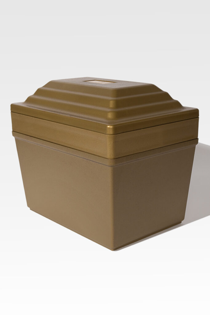 A stackable container with a gold finish and a tiered lid, similar to the Fortress® Urn Vault, is placed on a light gray background.