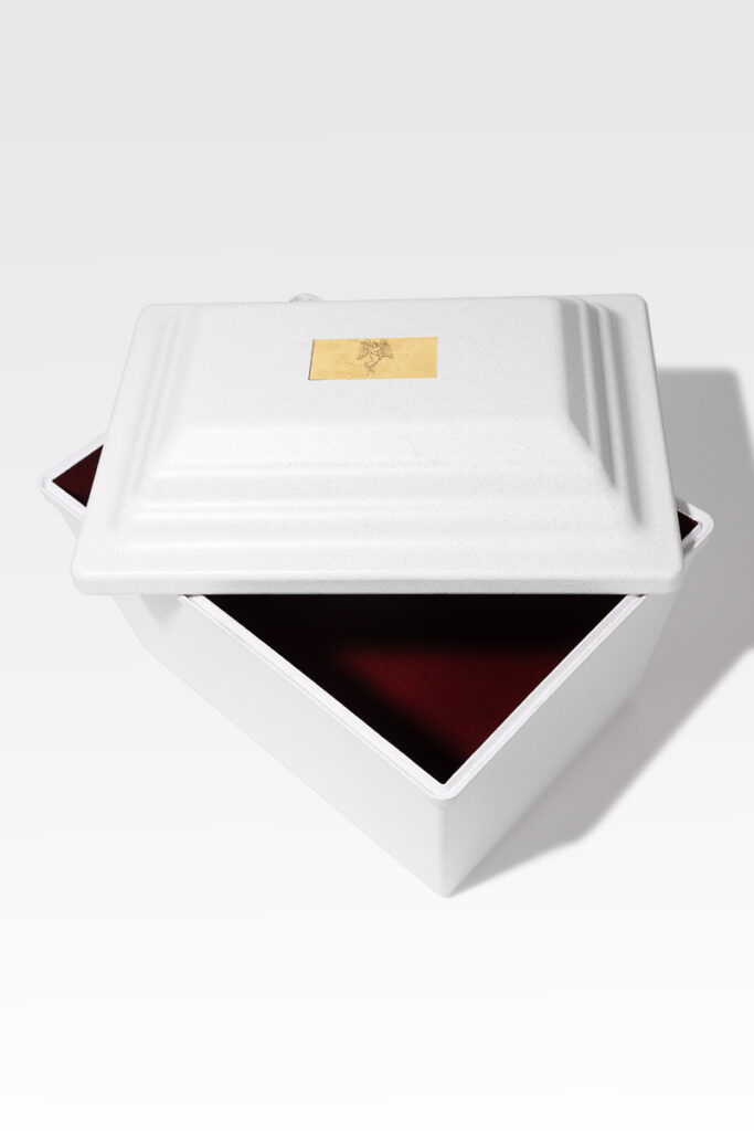 A white, square box with a partially open lid unveils a maroon interior that echoes the sophistication of a Fortress® Urn Vault, adorned with a gold emblem on its top.