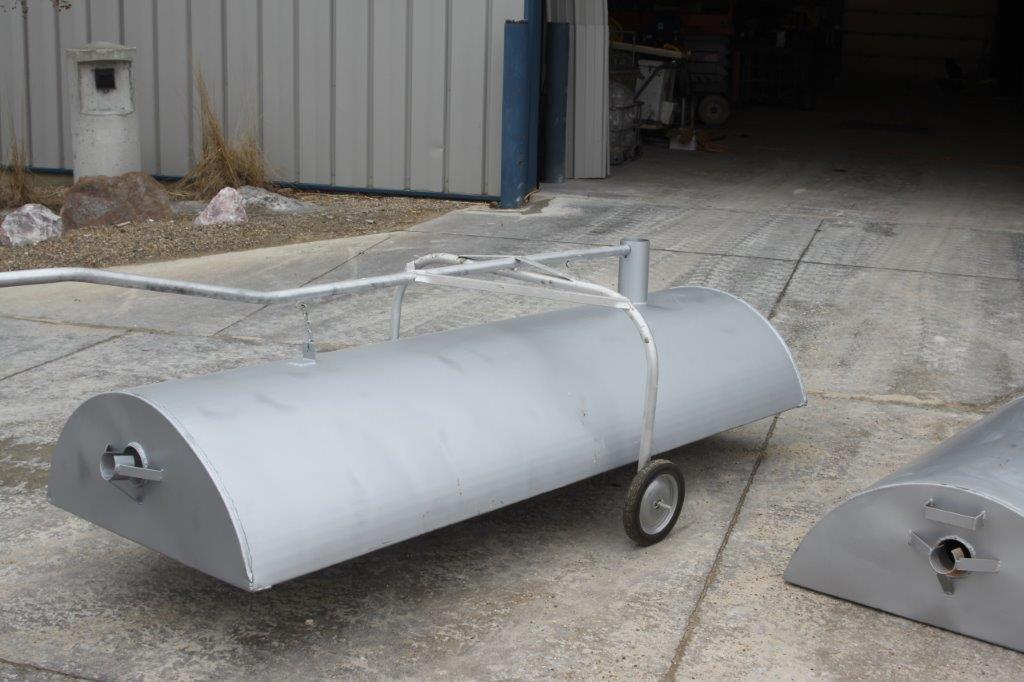 A top-tier cylindrical metal object with wheels is positioned outside a building. It features a curved top and handles for easy maneuvering, making it one of the top 10 cemetery products available.