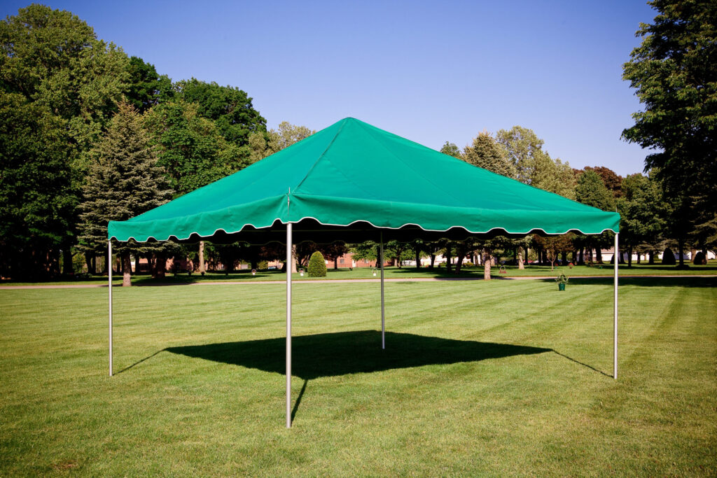 A green pop-up canopy tent, ideal for gatherings, is set up on a large grassy area surrounded by trees under a clear blue sky. This versatile tent often ranks among the top 10 cemetery products for its ease of use during memorial services.