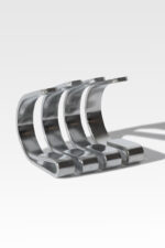 Four curved, polished metal strips are aligned parallel to each other, casting shadows on a plain white surface.