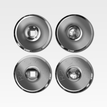 Four metallic circular objects are arranged in a square pattern, each with a central feature: two have square holes and two have rounded, textured centers.